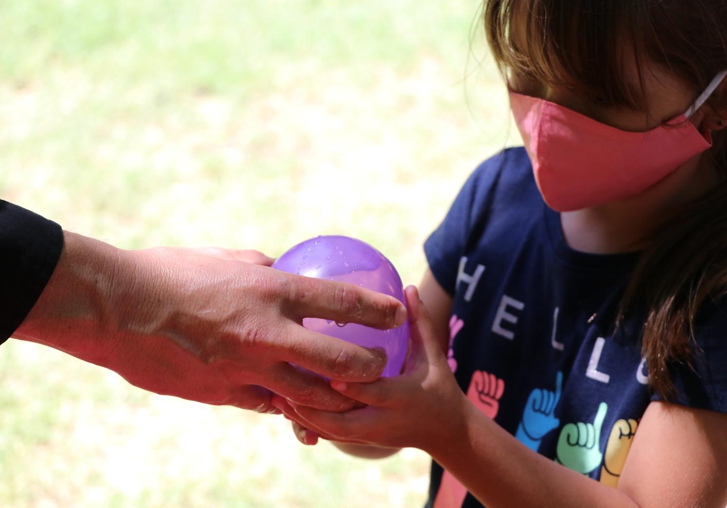 Kids playing water balloon toss game outdoors